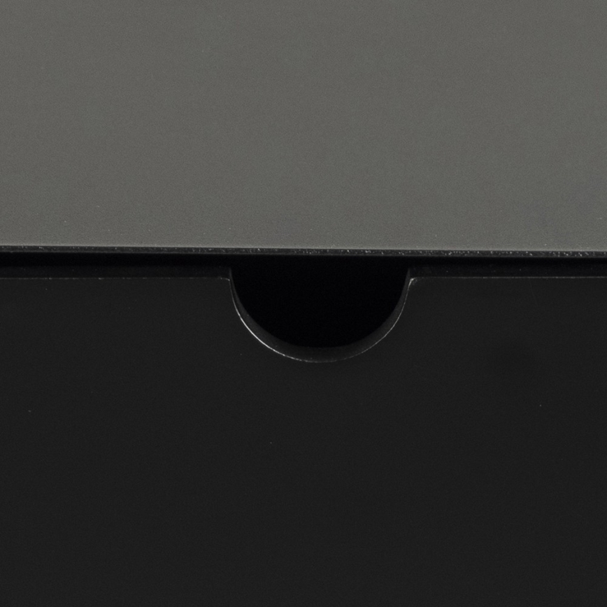 Šuplík je čiastočne otvorený. Viditeľná je tmavosivá vrchná časť a čierna spodná časť šuplíka. Vyrezaný otvor slúži na uchopenie a otvorenie šuplíka.