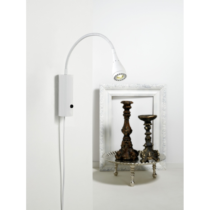 Biela nástenná lampa s ohybným ramenom smeruje svetlo na dve ozdobné svietniky na podnose. Lampa je pripevnená na stene a má vypínač na základni. Svietniky sú umiestnené v bielom ráme.