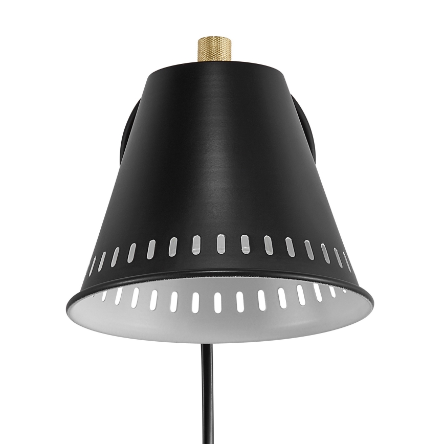 Čierna nástenná lampa s kužeľovitým tienidlom s otvormi, zlatým vrchnákom a čiernou kovovou ramenom, je zobrazená na bielom pozadí.