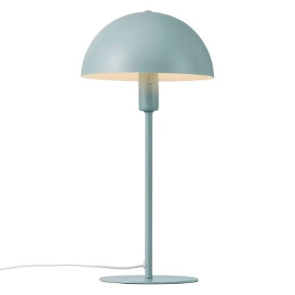 Stolová lampa s bledomodrým tienidlom v tvare huby stojí na rovnom podstavci. Lampa je pripojená na elektrickú sieť bielym káblom.