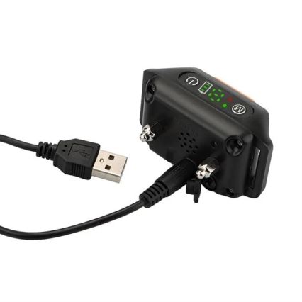 GPS obojok pre psov sa nabíja pomocou USB kábla. Obojok je čierny, má displej zobrazujúci 12:38 a tlačidlá. Je pripojený k USB adaptéru.