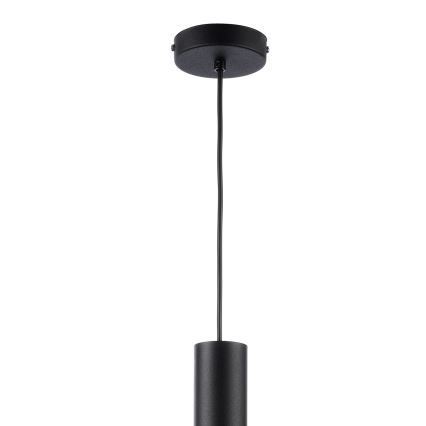 Čierna závesná lampa visí z čierneho stropného držiaka. Elektrický kábel spája držiak s valcovitým tienidlom. Pozadie je biele.
