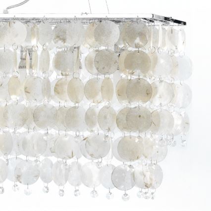 Svietidlo visí zo stropu. Je tvorené mnohými prekrývajúcimi sa okrúhlymi plátok svetlo béžovej farby, zavesenými na kovovom ráme a ozdobenými drobnými krištáľmi.