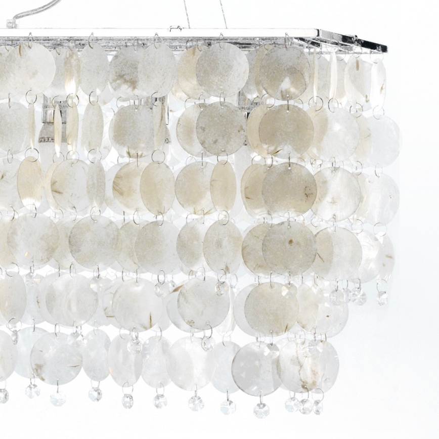 Svietidlo visí zo stropu. Je tvorené mnohými prekrývajúcimi sa okrúhlymi plátok svetlo béžovej farby, zavesenými na kovovom ráme a ozdobenými drobnými krištáľmi.