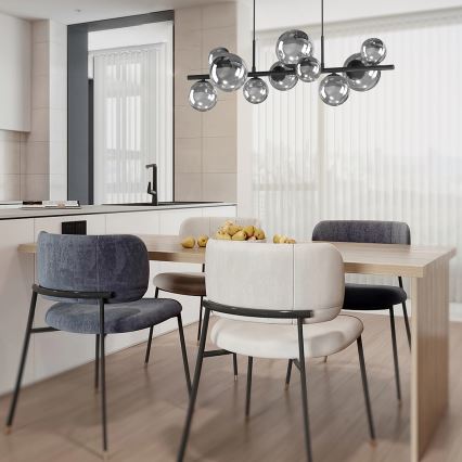 Svietidlo s viacerými guľovými tienidlami visí nad jedálenským stolom. Stôl je obklopený stoličkami z tmavošedej a svetlej látky. V pozadí sa nachádza kuchynská linka.