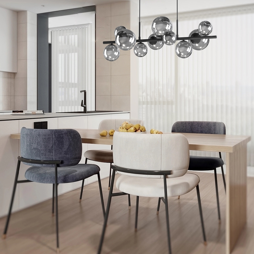 Svietidlo s viacerými guľovými tienidlami visí nad jedálenským stolom. Stôl je obklopený stoličkami z tmavošedej a svetlej látky. V pozadí sa nachádza kuchynská linka.