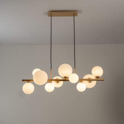 Zlatá stropná platnička s dvoma čiernymi káblami visí zhora. Káble siahajú smerom dole pred bielym pozadím.