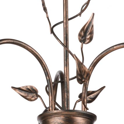Kovová lampa s ozdobnými listami sa nachádza na bielom pozadí. Lampa je medená s tmavšou patinou a má tri ramená zakončené ozdobnými kovovými listami.