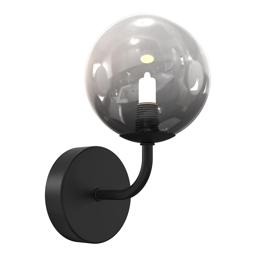 Nástená lampa s čiernym kovovým ramenom a sférickým tienidlom z dymného skla svieti. Tienidlo obsahuje žiarovku. Lampa je pripevnená k stene okrúhlou čiernou základňou.