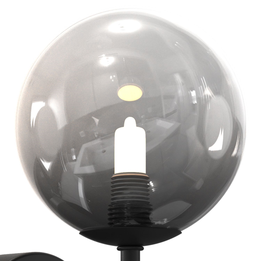 Svietidlo s guľovou tienidlom z tmavého skla chráni žiarovku. Tienidlo je pripevnené k čiernej kovovej základni. Na pozadí sa odráža kúpeľňa.