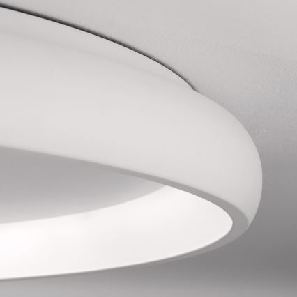 Biela stropná lampa s okrúhlym tvarom a vnútorným svetlom je pripevnená k stropu. Lampa je z jemného materiálu, vytvára jemné osvetlenie.