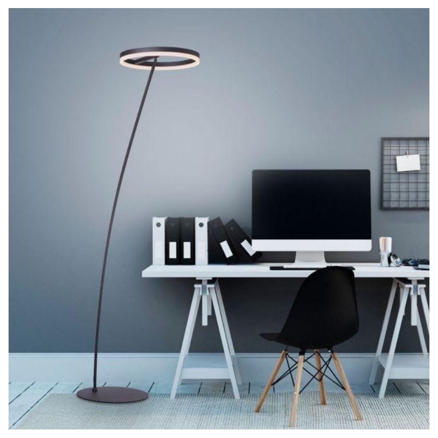 Stojacia lampa s kruhovým tienidlom stojí v pracovni. Lampa osvetľuje stôl s počítačom, kancelárskymi potrebami a stoličkou. Pozadie tvorí sivá stena.
