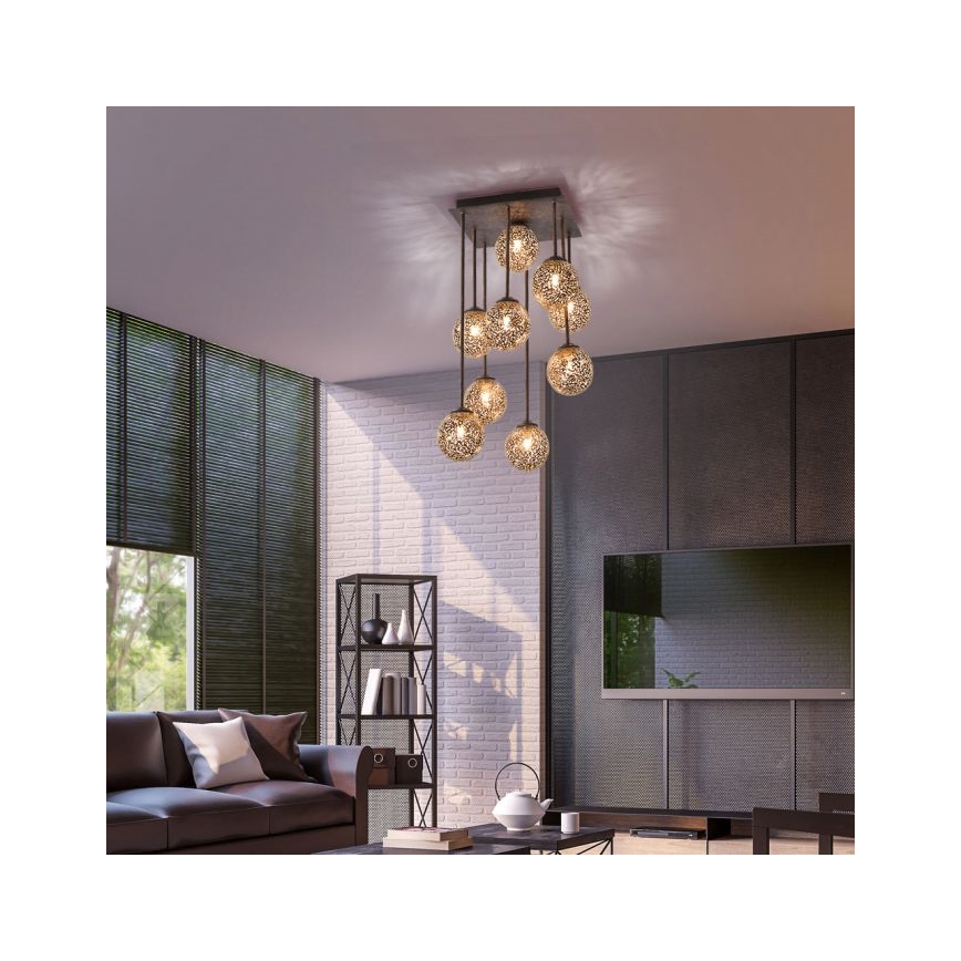 Viacramenná lustre s guľovými tienidlami visí zo stropu. Svetlá sú zavesené v obývacej izbe s pohovkou, regálom a televízorom.