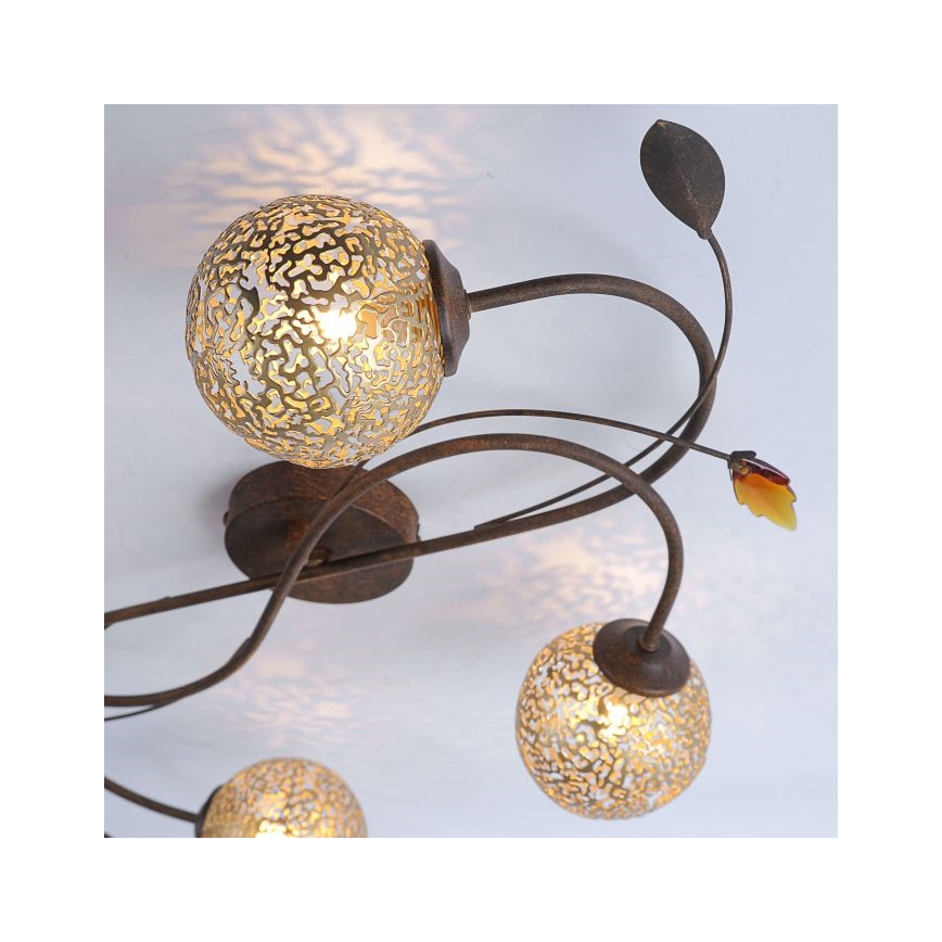 Stropné svietidlo s niekoľkými guľovitými tienidlami z perforovaného skla svieti. Kovové ramená svietidla sú tvarované ako vetvičky s listami. Svietidlo je pripevnené k stropu.