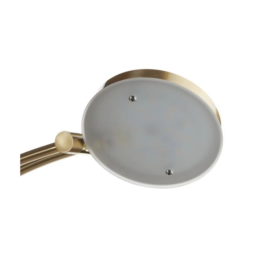 Svietidlo svieti. Základňa je zlatá, tienidlo matné, svetlo LED. Svietidlo je pripevnené k zakrivenej kovovej konštrukcii.