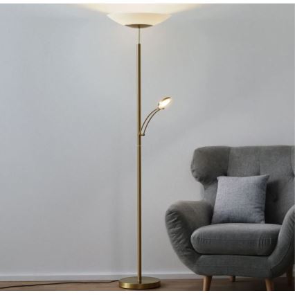 Stojacia lampa s dvoma zdrojmi svetla, s väčším tienidlom a menším otočným svetlom, stojí v blízkosti sivej kresla.