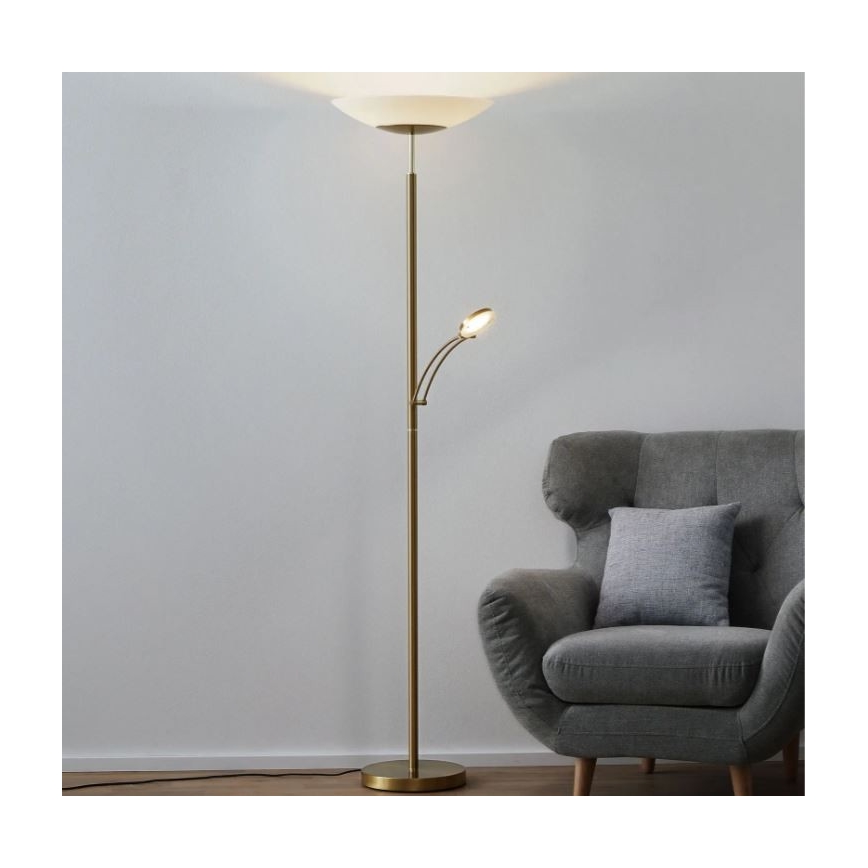 Stojacia lampa s dvoma zdrojmi svetla, s väčším tienidlom a menším otočným svetlom, stojí v blízkosti sivej kresla.