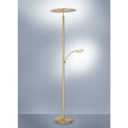 Stojacia lampa s dvoma svetlami stojí na podlahe pred svetlomodrým pozadím. Hlavné svetlo je ploché, horné, zatiaľ čo menšie, bočné svetlo je na ohybnom rameni. Lampa je zlatohnedej farby.