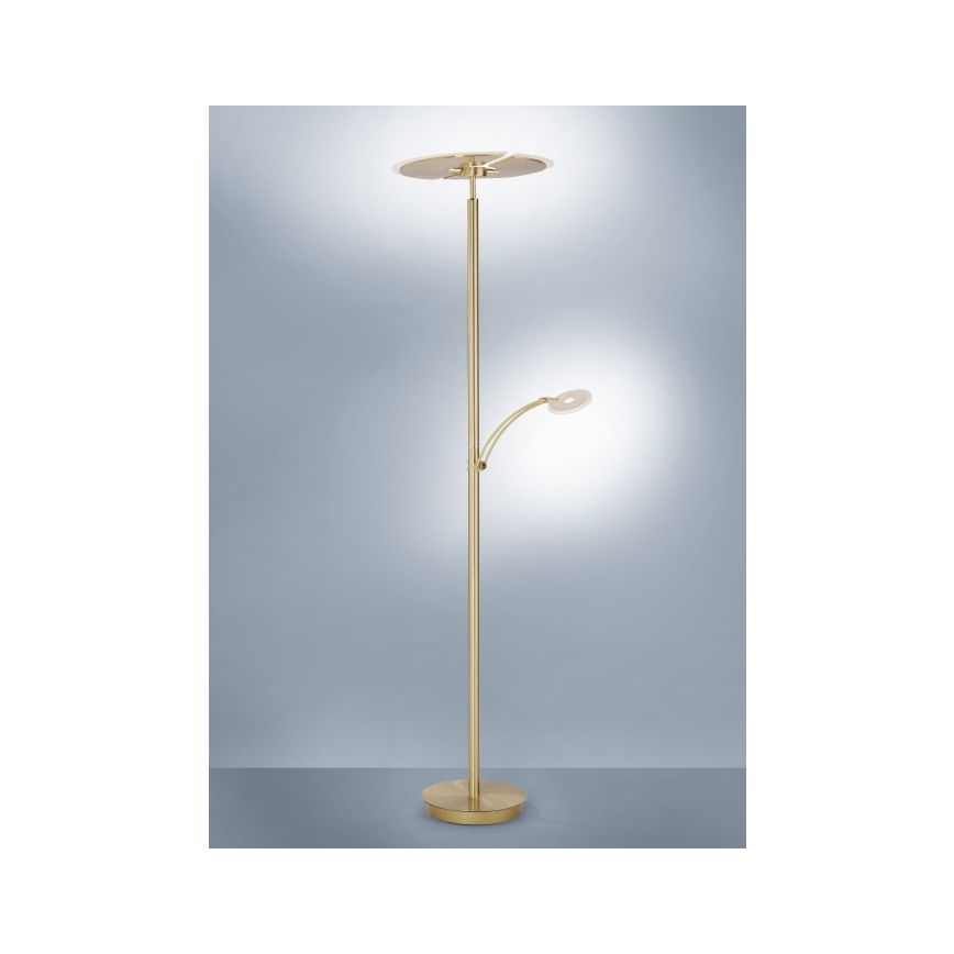 Stojacia lampa s dvoma svetlami stojí na podlahe pred svetlomodrým pozadím. Hlavné svetlo je ploché, horné, zatiaľ čo menšie, bočné svetlo je na ohybnom rameni. Lampa je zlatohnedej farby.