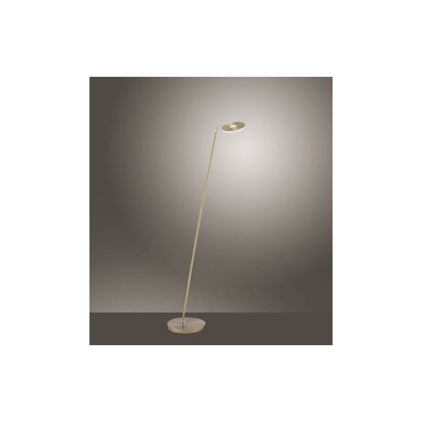 Stojacia lampa s vysokou kovovou tyčou a kruhovou hlavou svieti. Je umiestnená na svetlohnedej podlahe pred neutrálnou stenou.