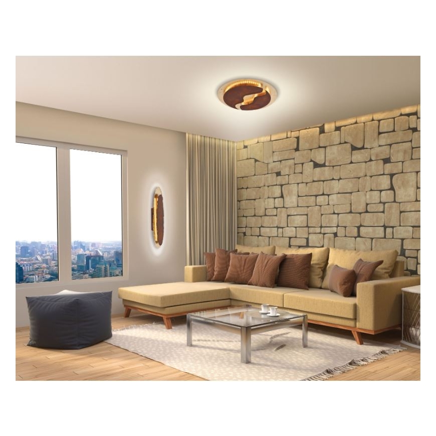 Stropné svietidlo s hnedým a zlatým dizajnom osvetľuje modernú obývačku s rohovou sedačkou, kávovým stolíkom a stenou z kameňa. Vedľa sedačky je umiestnené nástenné svietidlo podobného dizajnu.