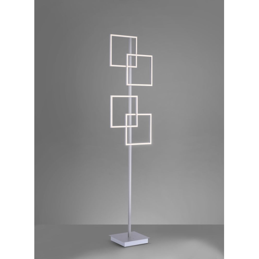 Stojacia lampa s vysokým stĺpikom a štvorcovými LED svetlami. Svetlá sú usporiadané v dvoch pároch, prekrývajúcich sa na stĺpiku. Lampa stojí na štvorcovej základni na jednotnej sivej ploche.