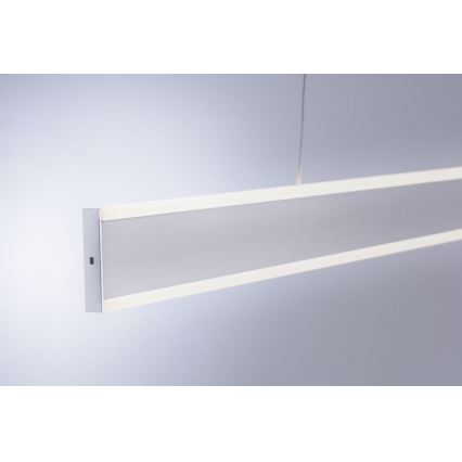 Dlhá obdĺžniková LED lampa visí zo stropu. Je strieborno-sivej farby s tenkým bielym LED osvetlením pozdĺž hornej a dolnej hrany. Svetlo je umiestnené v jednoduchom, neutrálnom prostredí.