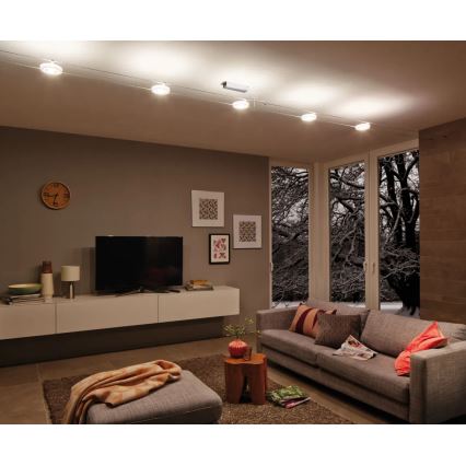 Svietidlo s piatimi bodovými svetlami osvetľuje modernú obývaciu izbu. Izba obsahuje sedačku, televízor, konferenčný stolík a výhľad na zasneženú krajinu cez veľké okná.