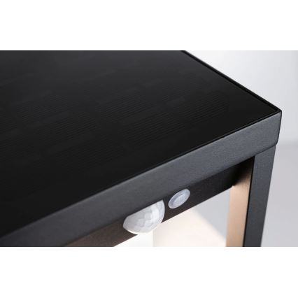 Solárny stolík s integrovaným senzorom pohybu a prepínačom stojí na svetlom pozadí. Vrchná doska stolíka slúži ako solárny panel.