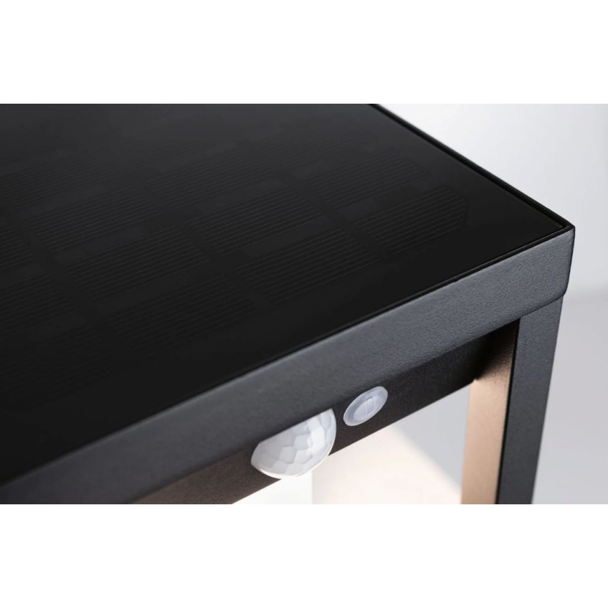 Solárny stolík s integrovaným senzorom pohybu a prepínačom stojí na svetlom pozadí. Vrchná doska stolíka slúži ako solárny panel.