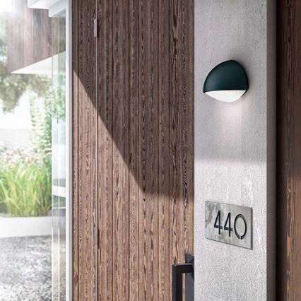 Vonkajšie nástenné svietidlo svieti pri dverách. Číslo domu je 440. Svietidlo je namontované na betónovom stĺpe vedľa drevených dverí.
