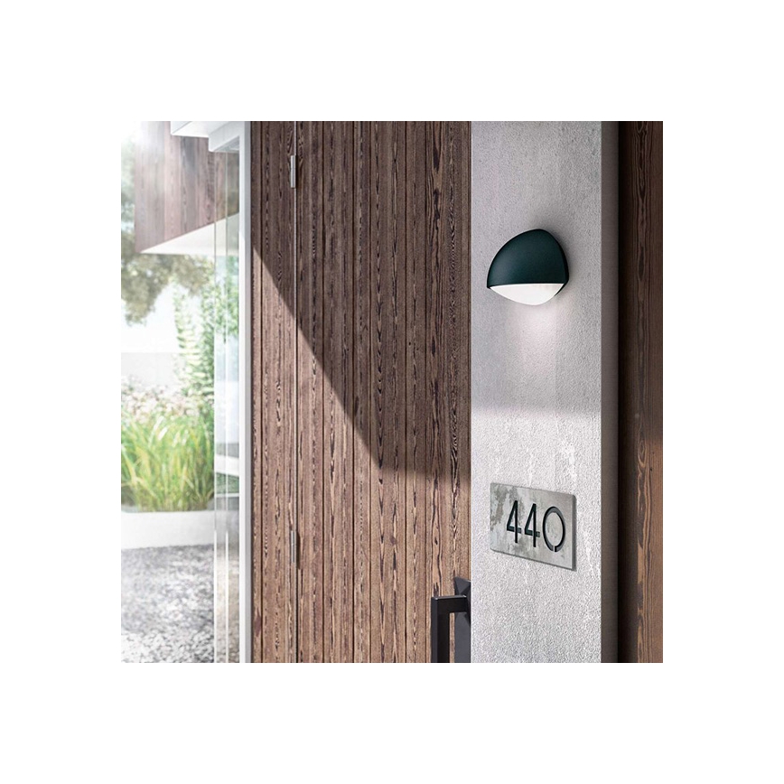 Vonkajšie nástenné svietidlo svieti pri dverách. Číslo domu je 440. Svietidlo je namontované na betónovom stĺpe vedľa drevených dverí.