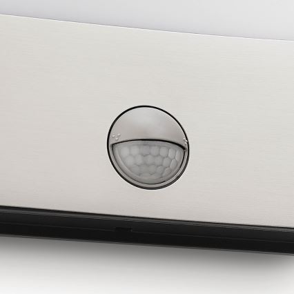 Senor detekuje pohyb. Je umiestnený na kovovej svietidlovej konštrukcii. Svietidlo má čierny spodný okraj.