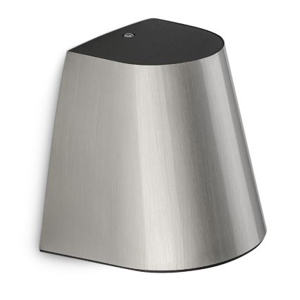 Strieborná nástenná lampa s tmavosivým vrchnákom je pripevnená na stenu. Svetlo je smerované nadol. Lampa má asymetrický tvar.