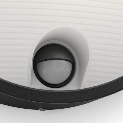 Senzor detekuje pohyb. Nachádza sa vo vnútri vonkajšieho svietidla s bielym difúznym krytom a čiernym rámom.