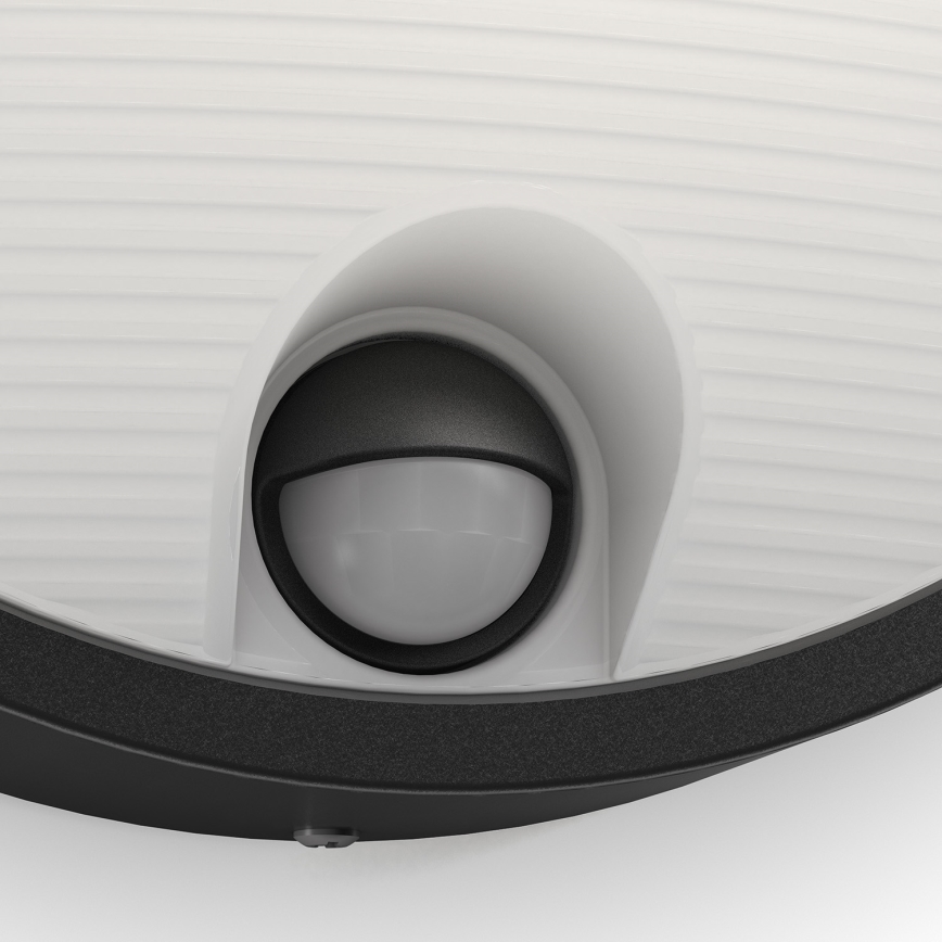 Senzor detekuje pohyb. Nachádza sa vo vnútri vonkajšieho svietidla s bielym difúznym krytom a čiernym rámom.