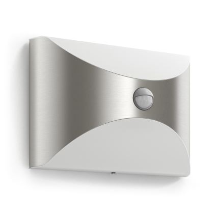 Svietidlo s pohybovým senzorom je namontované na stene. Jeho oblúkový tvar kombinuje striebornú a bielu farbu. Senzor je umiestnený v strede kovového prvku.