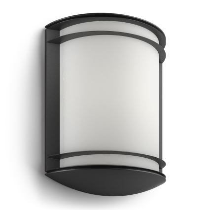 Nástená lampa s valcovitým mliečnym difúzorom je umiestnená na stene. Je tmavosivá s čiernym rámom.