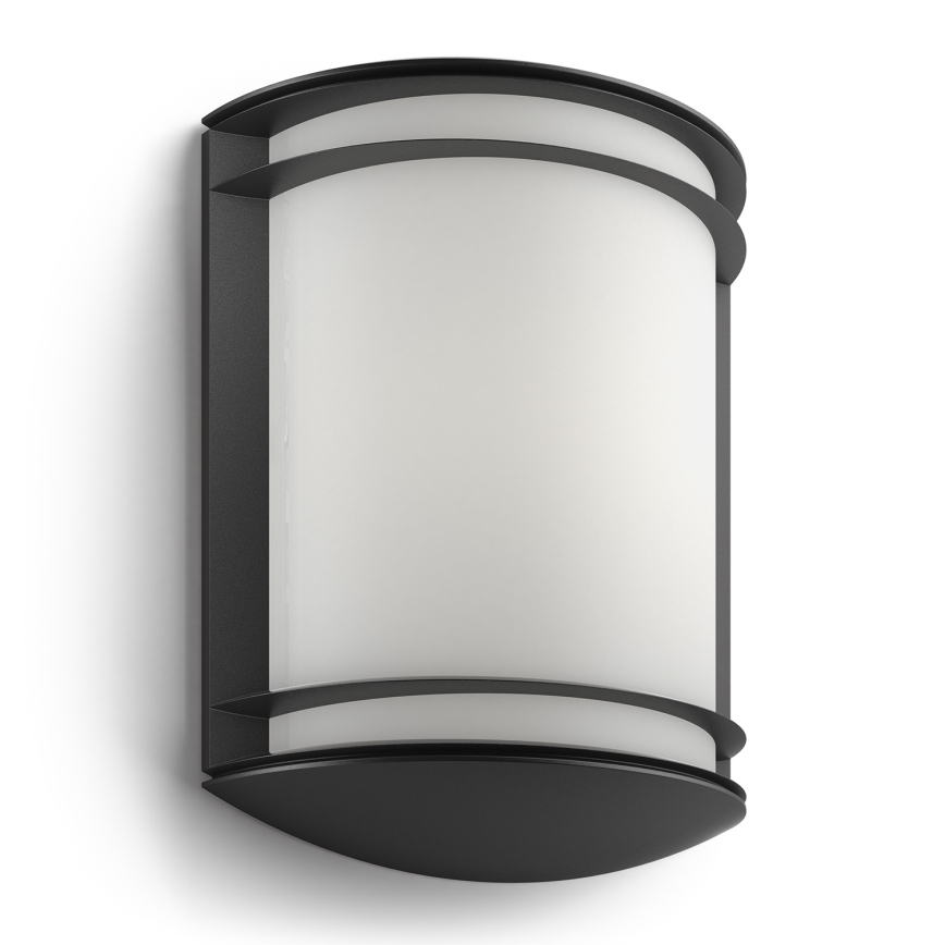 Nástená lampa s valcovitým mliečnym difúzorom je umiestnená na stene. Je tmavosivá s čiernym rámom.