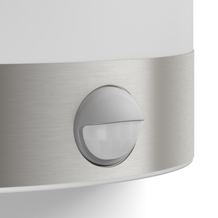 Senzor pohybu detekuje pohyb. Je umiestnený na kovovom páse, ktorý je súčasťou steny svietidla. Svietidlo je biele, s kovovou časťou.