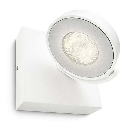 Biela nástenná LED lampa s okrúhlym, otočným reflektorom svieti. Je pripevnená na štvorcovej bielej základni na stenu.