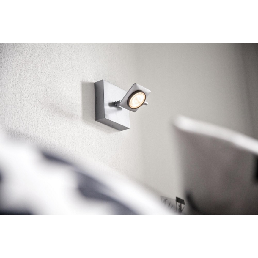 Svietidlo svieti na stene. Je otočné a pripevnené na štvorcovom podstavci. Nachádza sa v blízkosti postele.