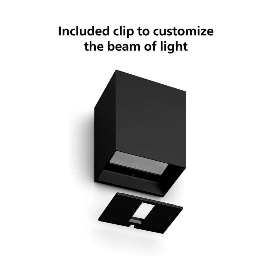Čierna nástenná lampa s odnímateľným klipom na úpravu svetelného lúča. Klip je umiestnený pod lampou. Text: „Included clip to customize the beam of light“.