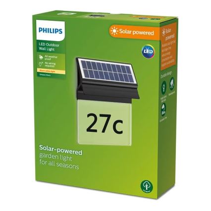 Solárna záhradná lampa Philips s číslom 27c je zobrazená na obale. Lampa je pripevnená na stene a je napájaná solárnym panelom. Balenie oznamuje, že je odolné voči poveternostným vplyvom, nevyžaduje zapojenie do siete a vydáva teplé biele svetlo.