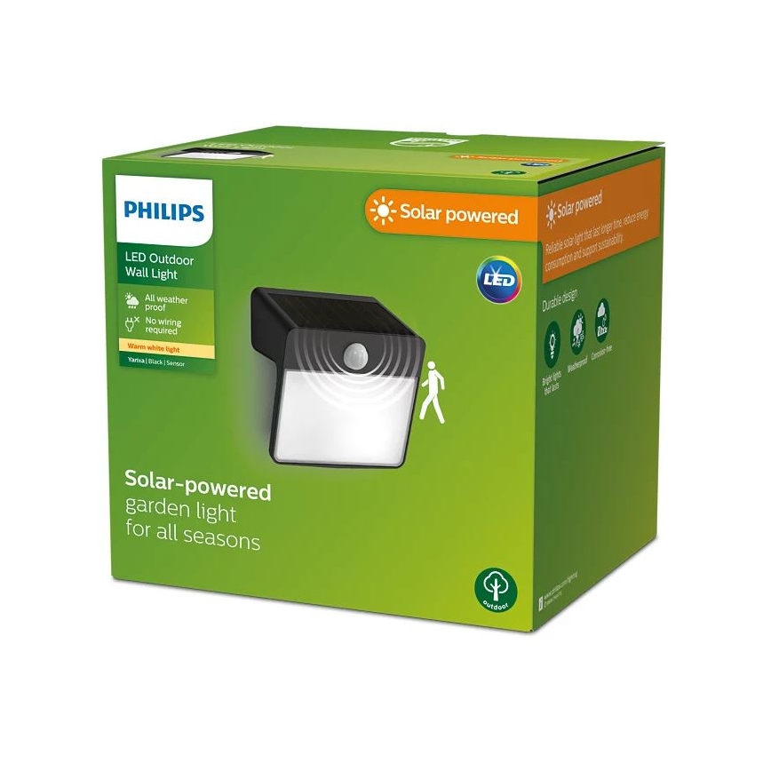 Solárna nástenná lampa Philips s detektorom pohybu je zobrazená na obale. Lampa svieti teplým bielym svetlom, je odolná voči poveternostným vplyvom a nevyžaduje žiadne káblovanie. Balenie uvádza: Solárna nástenná lampa Philips, LED vonkajšie osvetlenie, všetko počasie, bez zapojenia, teplé biele svetlo, Varianta: čierna, senzor.