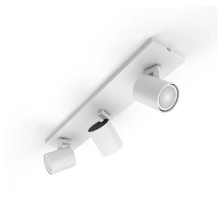 Trojité stropné svietidlo s bielym matným povrchom je pripevnené k stropu. Tri nastaviteľné reflektory smerujú dolu. Svietidlo je umiestnené na bielom pozadí.