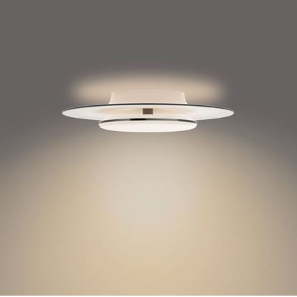 Svietidlo svieti na strop. Je tvorené dvoma prekrývajúcimi sa bielymi diskovými prvkami s kovovou úpravou medzi nimi, pripevnené k stropu. Svetlo je teplej farby.