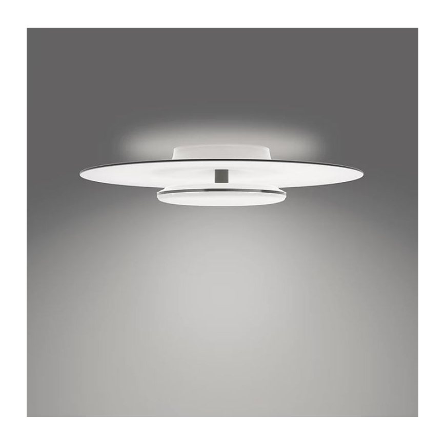 Svietidlo svieti na sivom pozadí. Skladá sa z dvoch bielych diskov, menší je na vrchu väčšieho, spojené tenkým kovovým lemom. Svietidlo je pripevnené k stropu.