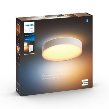 Okrúhle stropné svetlo Philips Hue svieti teplým bielym svetlom. Balenie zobrazuje svetlo inštalované a obsahuje text: „Philips hue White ambiance Enrave M ceiling light. Personalize your home with smart lighting.“