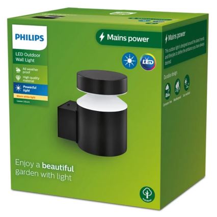 Čierna LED nástenná lampa Philips svieti. Je zabalená v zelenej krabici s popisom: LED Outdoor Wall Light, Mains power, All weather proof, High quality material, Powerful light, Warm white light, Laven|Black, a Enjoy a beautiful garden with light.